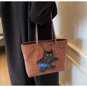 Detail of suede tote bag featuring a cute black cat embroidery with a small fish bag
