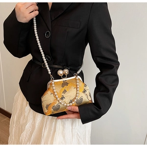 Close-up of golden brocade evening bag with crane embroidery and pearl strap details