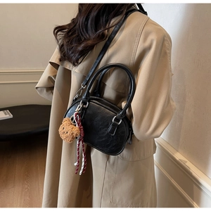 Detail of black PU Boston bag with silver hardware and brown teddy bear charm