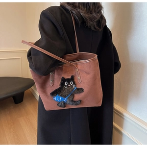 Close-up of brown canvas tote bag featuring black cat embroidery and long shoulder strap