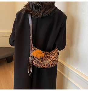 Detail of leopard print crossbody bag with leather strap and plush dog charm on model