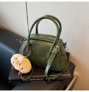 Details der dunkelgrünen Retro-Bowlingtasche mit weißen Nähten und Plüsch-Anhänger