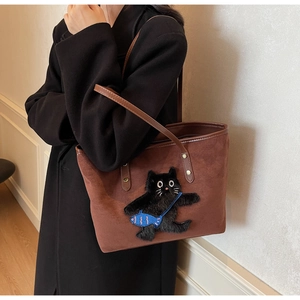 Detail of a brown suede tote bag featuring a cute cat and fish embroidery pattern