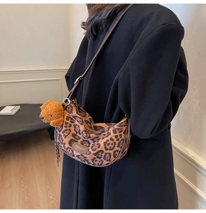Detail of leopard print hobo bag with adjustable leather strap and a plush dog charm