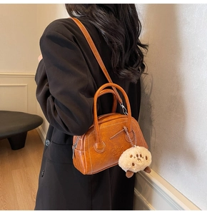 Nahaufnahme der braunen Vintage-PU-Leder-Tasche mit Plüsch-Anhänger und Logo-Detail