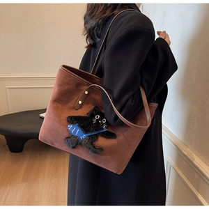 Detail of brown suede tote bag with black cat patch embroidery and leather straps