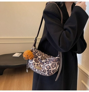 Close-up of leopard print canvas crossbody bag with brown leather strap and puppy charm