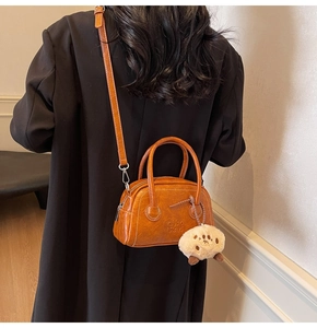 Detail einer vintage orangebraunen Leder-Bostontasche mit weißem Alpaka-Anhänger
