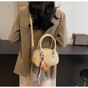 Detail of beige boston bag with silk scarf, teddy charm and adjustable shoulder strap