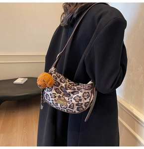 Detail of leopard print hobo bag with brown strap and cute teddy bear charm accessory