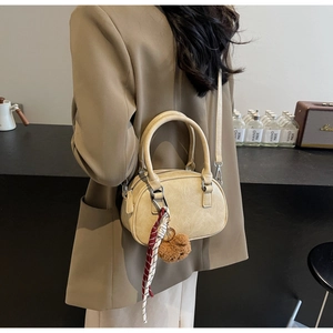 Detail of beige Boston bag with faux leather texture and plush bear charm accessory