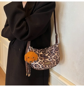 Detail of leopard print hobo bag with teddy charm and adjustable leather strap