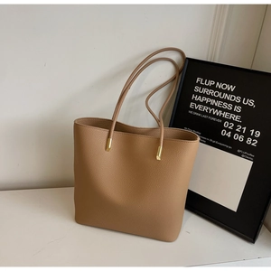 Minimalist tan pebbled leather tote bag with elegant golden cylindrical hardware details