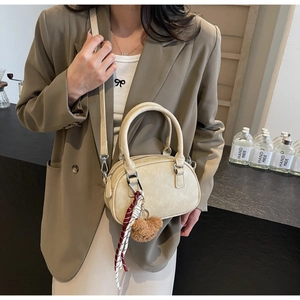 Detail of cream Boston bag with plush bear charm and plaid scarf on adjustable strap
