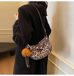 Leopard print crescent bag featuring a brown teddy dog charm and classic brand tag details