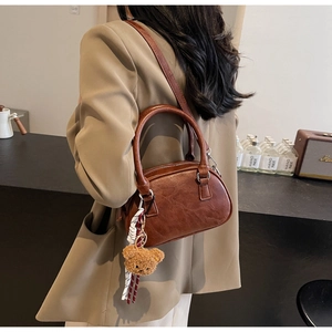 Close-up of brown vintage Boston bag with oil wax leather texture and bear charm