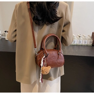 Rear view of model wearing a vintage brown crossbody pillow bag with bear charm and ribbon