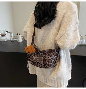 Detail of leopard print hobo bag with plush teddy charm and golden hardware accents