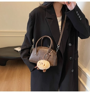Detail der vintage braunen Ledertasche mit Plüschanhänger und Logo-Prägung auf dem Leder