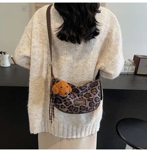 Detail of leopard print hobo bag with plush teddy bear charm and adjustable leather strap
