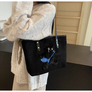 Detail of black suede tote bag featuring a plush 3D cat embroidery and blue fish pouch