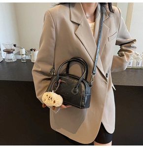 Detail einer schwarzen Bowling-Tasche mit weißen Nähten und flauschigem Anhänger