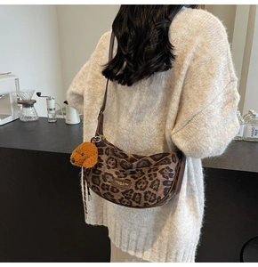 Detailed view of leopard print hobo bag with leather strap and cute teddy bear charm