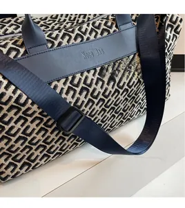 Detail of jacquard weave texture and leather brand patch on large travel tote bag