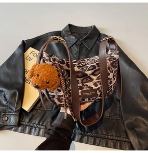 Close-up of leopard print shoulder bag with brown leather strap and plush dog charm