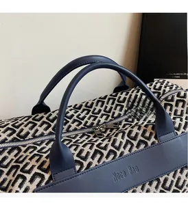 Detailed close-up of woven geometric fabric and premium leather handles on travel bag