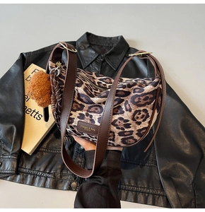 Detail of leopard print hobo bag with plush bear charm and vintage leather brand patch