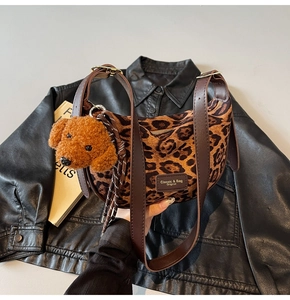 Detail of leopard print crescent bag with leather strap and plush dog keychain