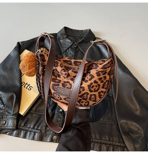 Detail of leopard print hobo bag featuring brown leather strap and plush bear charm