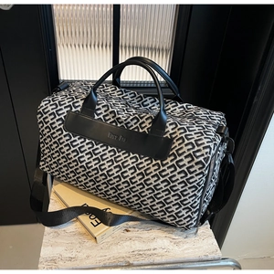 Close-up of geometric woven travel bag featuring black leather handles and logo details