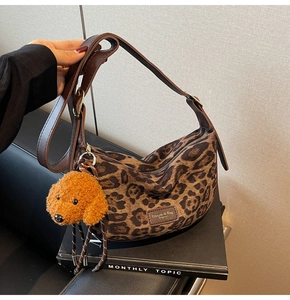 Detail showing the leopard print canvas texture and cute orange plush puppy bag charm