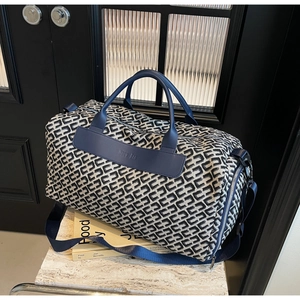 Detail of navy canvas duffel bag with geometric pattern and premium leather handles