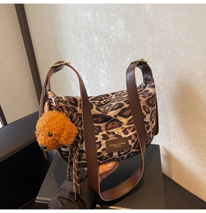 Detail of leopard print crossbody bag featuring faux fur texture and a cute teddy bear charm