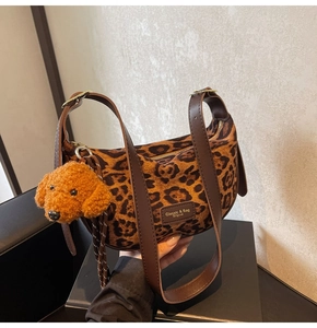 Detail of leopard print suede bag featuring a leather logo patch and cute plush dog charm