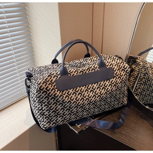 Detail of blue geometric jacquard travel bag with leather handles and HOCO BAG logo