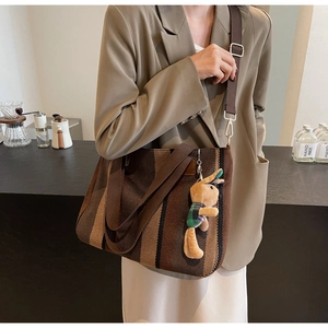 Detail of striped canvas tote bag with adjustable shoulder strap and cute bunny pendant