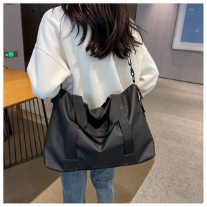 Large black waterproof oxford travel bag with adjustable strap shown on a model