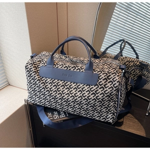 Detailed view of large travel bag featuring geometric monogram pattern and leather straps