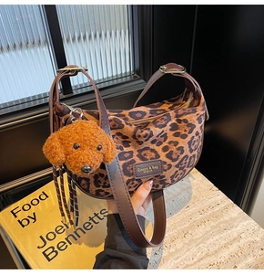 Close-up of leopard print crossbody bag with plush puppy charm and metallic buckle detail