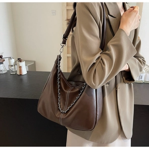Detail der dunkelbraunen Hobo-Tasche mit Kontrastnaht und Silberkette am Model getragen