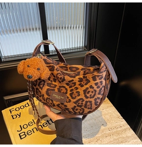 Detail of leopard print hobo bag with leather strap and cute brown teddy charm
