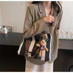 Striped canvas tote bag with brown handles and a cute bunny plush charm on a model