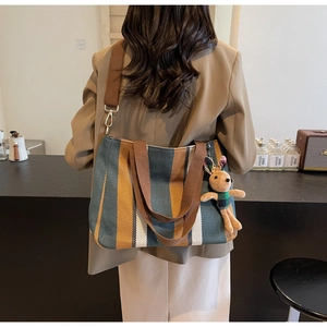 Detail of striped canvas tote bag with brown shoulder strap and cute rabbit pendant
