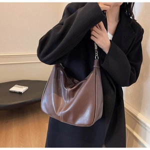 Seitenansicht der großen braunen Ledertasche mit weißen Nähten und silberner Metallkette