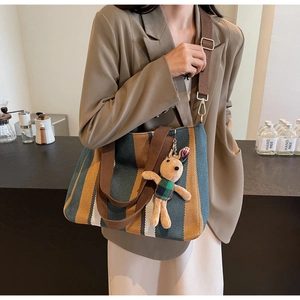 Detail of striped canvas tote bag with adjustable brown shoulder strap and bunny charm