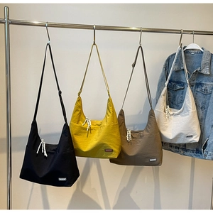 Detailansicht von vier minimalistischen Halbmond-Tragetaschen in Erdtönen an einem Ständer